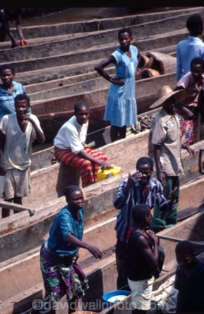 dugout;canoe;canoes;stack;stacked;pile;pile_up;person;people;men;man;women;woman;trade;trading;trader;traders;buy;buying;sell;selling;produce;river;wait;waiting;congo;zaire;democratic-republic-of-congo