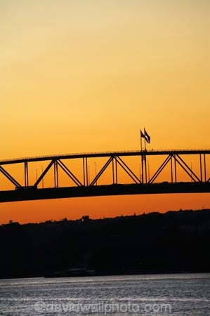 Auckland;Auckland-Harbour-Bridge;bridge;bridges;dusk;evening;flag;flags;N.I.;N.Z.;New-Zealand;NI;nightfall;North-Island;NZ;orange;silhouette;silhouettes;sky;span;spans;steel;structure;structures;sunset;sunsets;transport;transportation;twilight;Waitemata-Harbor;Waitemata-Harbour