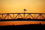 Auckland;Auckland-Harbour-Bridge;bridge;bridges;dusk;evening;flag;flags;N.I.;N.Z.;New-Zealand;NI;nightfall;North-Island;NZ;orange;silhouette;silhouettes;sky;span;spans;steel;structure;structures;sunset;sunsets;transport;transportation;twilight