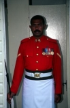 guard;guarding;stand;standing;uniform;red;white;shirt;belt;medal;medals;doorway;headquarters